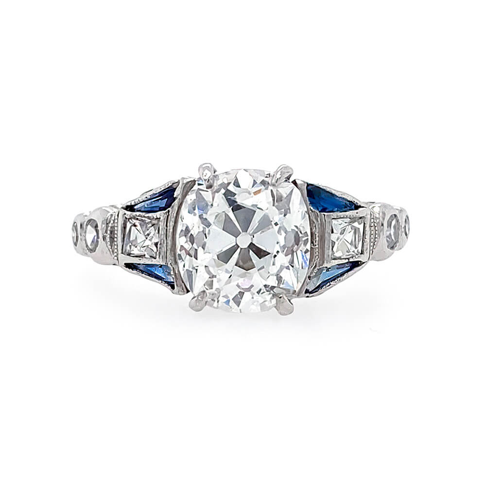 An Art Deco style diamond ring featuring a large center diamond with smaller diamonds set into the platinum band and blue sapphire accent stones .
