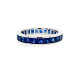 A platinum eternity band ring with channel set blue sapphires.