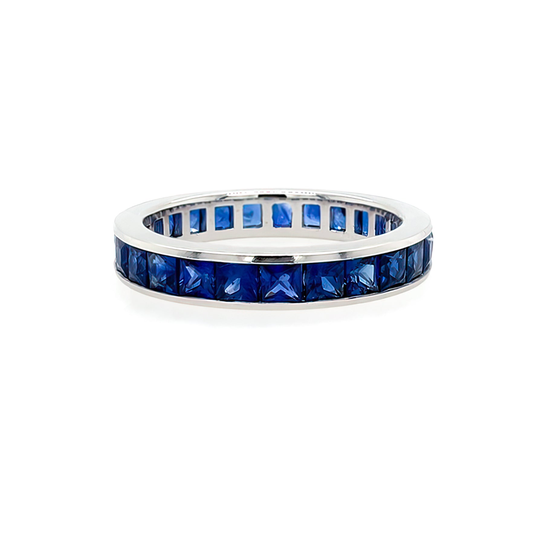 A platinum eternity band ring with channel set blue sapphires.