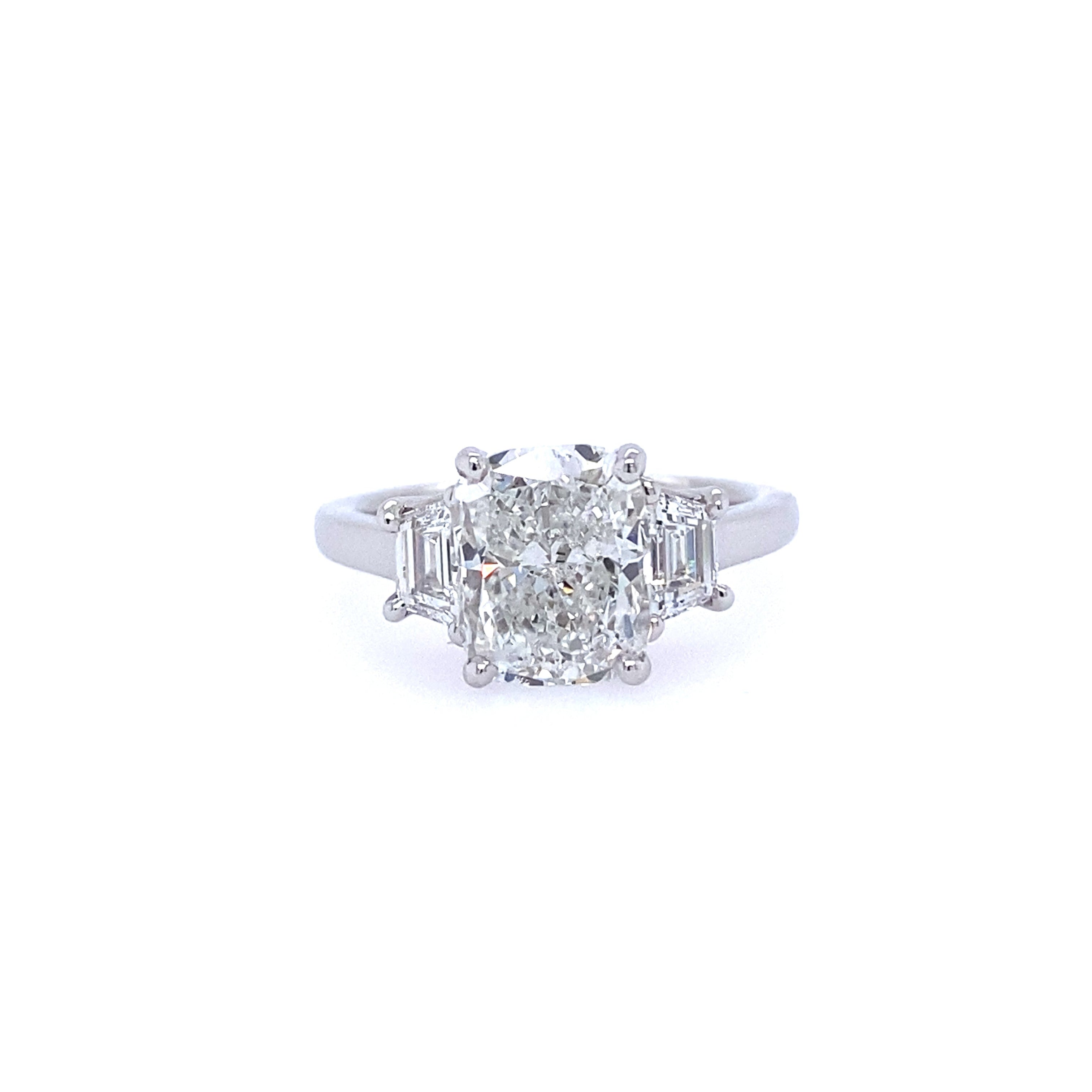 A platinum cushion cut diamond ring with step-cut trapezoid side stones