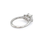 A platinum diamond ring with a cushion-cut center stone in a four-prong setting, shown from a side angle on a plain white background.