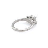 A platinum diamond ring with a cushion-cut center stone in a four-prong setting, shown from a side angle on a plain white background.