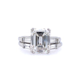 An emerald cut diamond ring with smaller baguette cut diamonds on the sides, set in a platinum band.