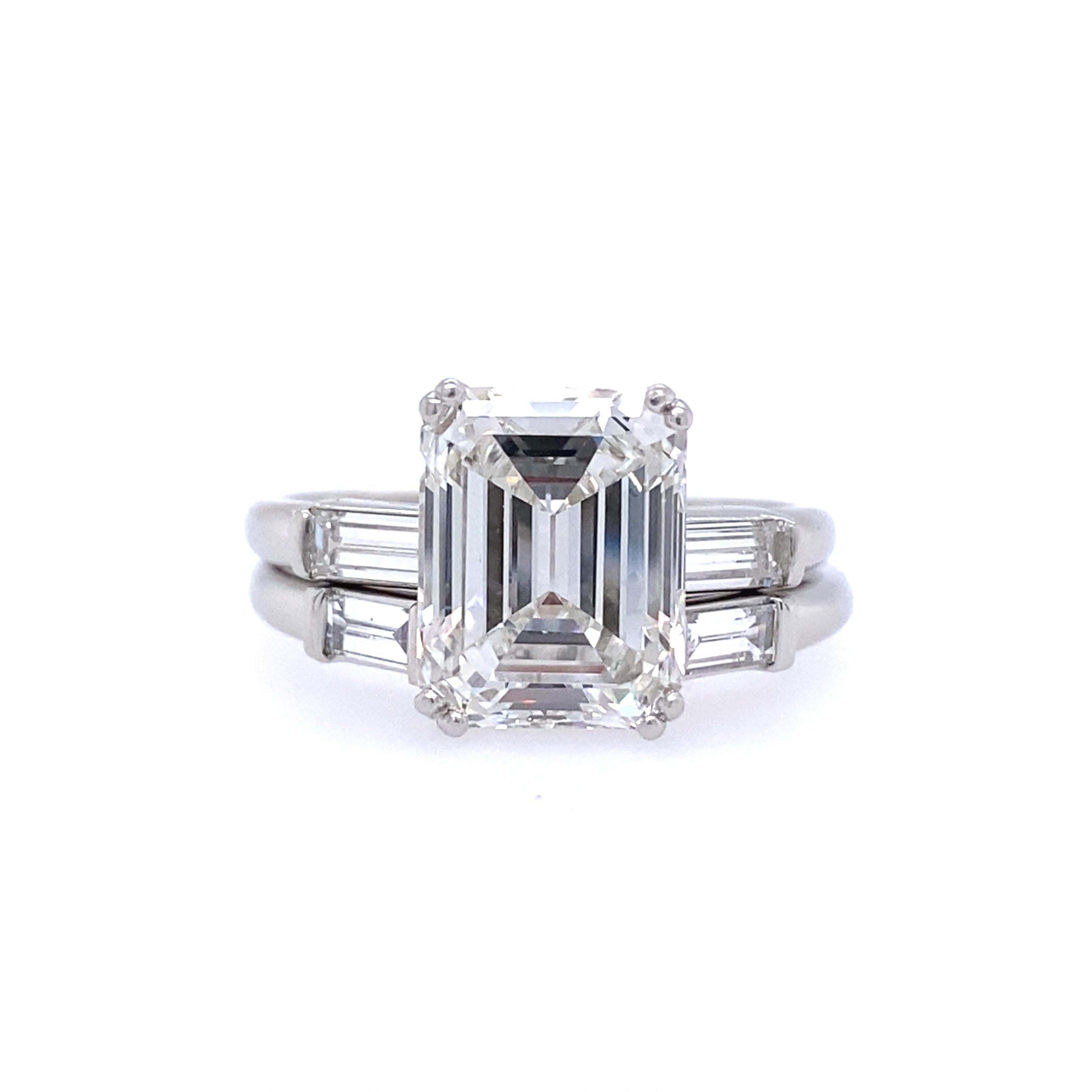 An emerald cut diamond ring with smaller baguette cut diamonds on the sides, set in a platinum band.