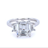 A platinum emerald cut diamond ring with trapezpoids on a white background