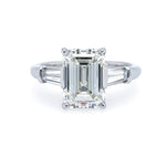 Custom platinum engagement ring with emerald-cut center diamond and baguette side dimaonds on a white background
