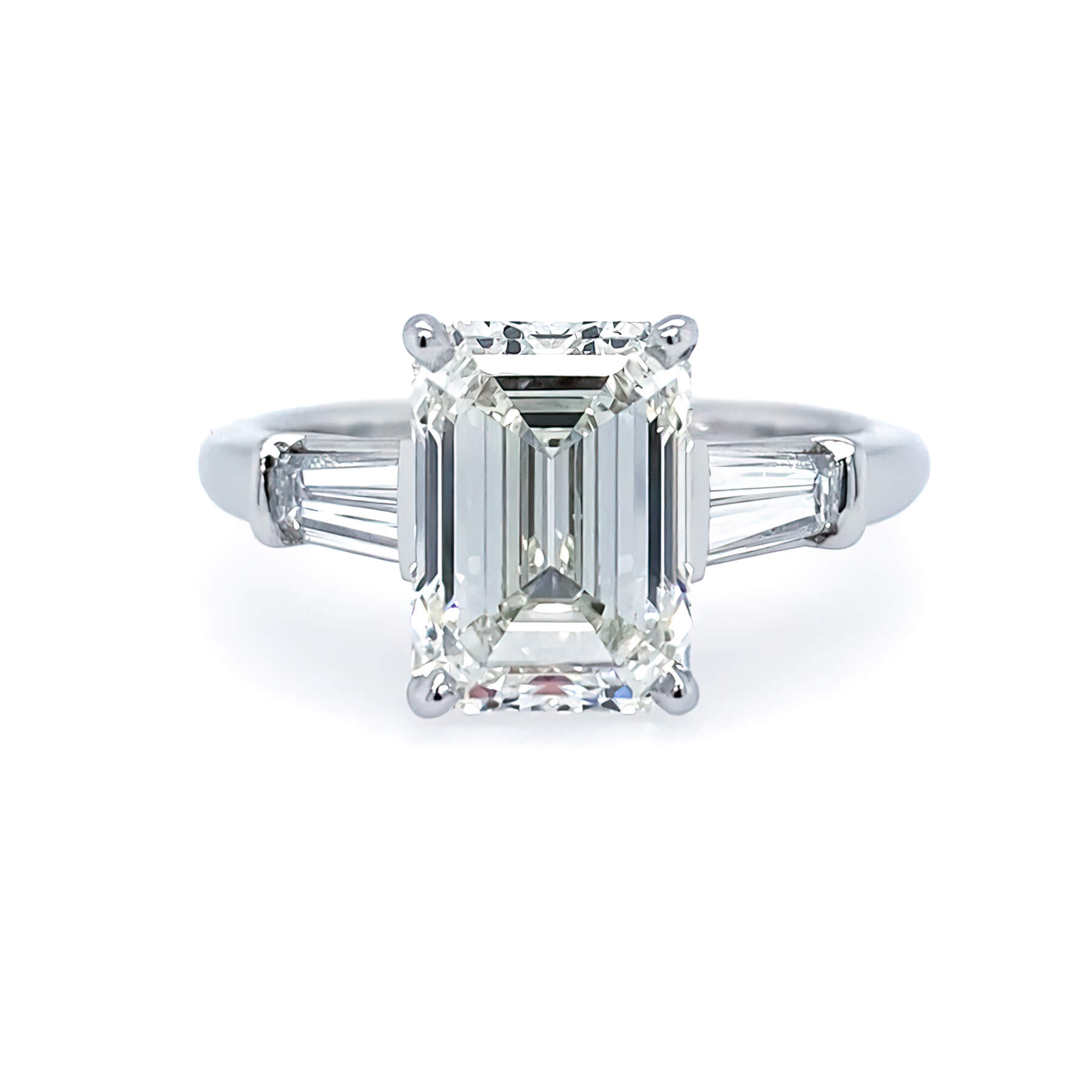 Custom platinum engagement ring with emerald-cut center diamond and baguette side dimaonds on a white background