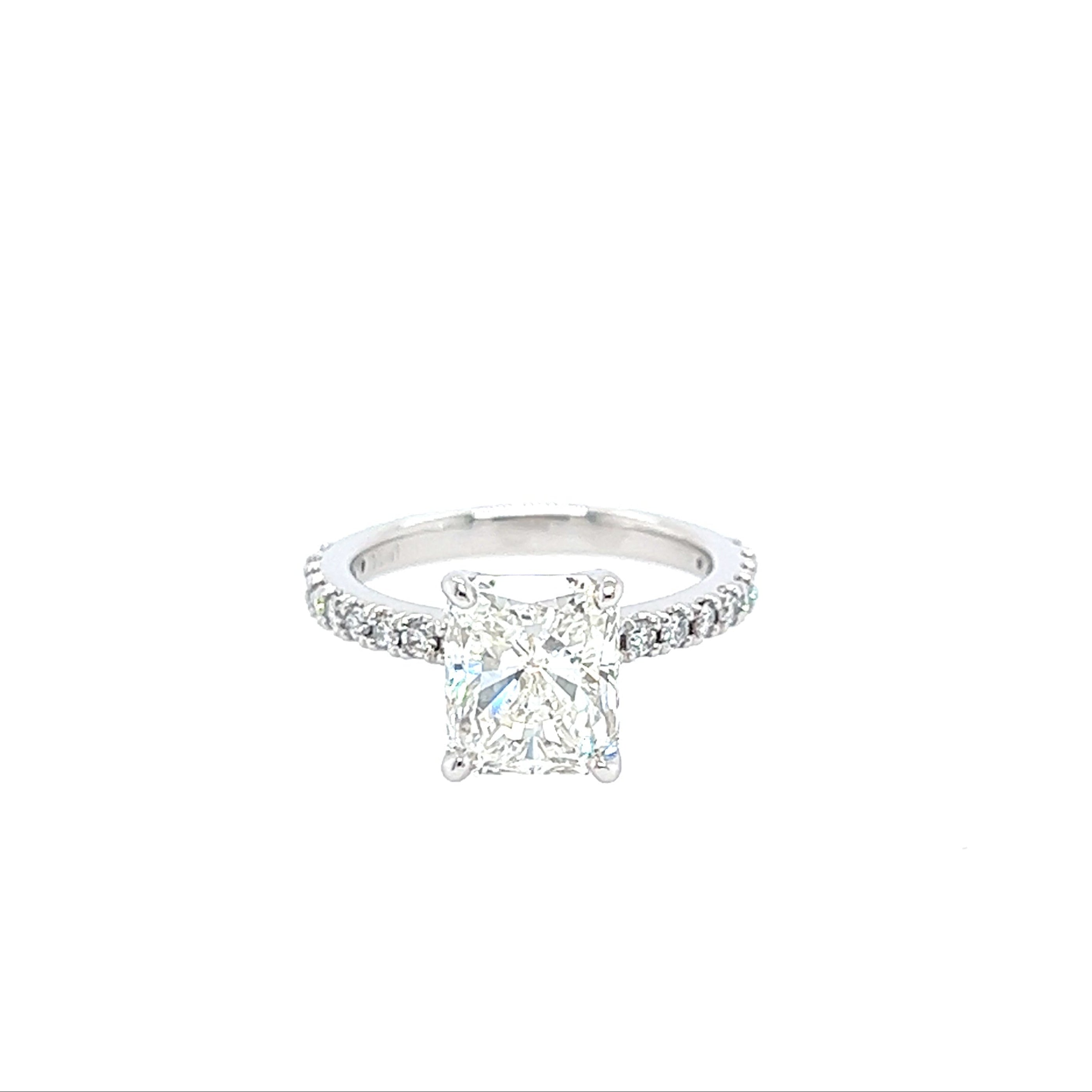 A Platinum and Diamond Radiant Cut Engagement Ring with a clear central diamond and smaller diamonds on the band, set against a white background.