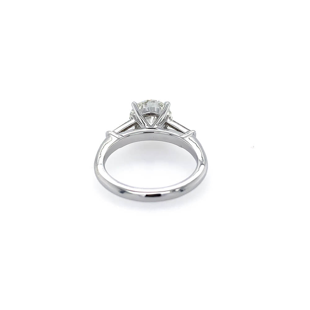 A platinum diamond engagement ring with a round brilliant center stone and side tapered baguette stones, shown on a plain white background.