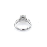 A platinum diamond engagement ring with a round brilliant center stone and side tapered baguette stones, shown on a plain white background.