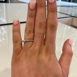 A close-up of a woman wearing a thin platinum band ring with round and baguette diamonds 