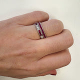 Close-up of a woman's hand wearing a platinum eternity band ring with red ruby gemstones and diamonds 