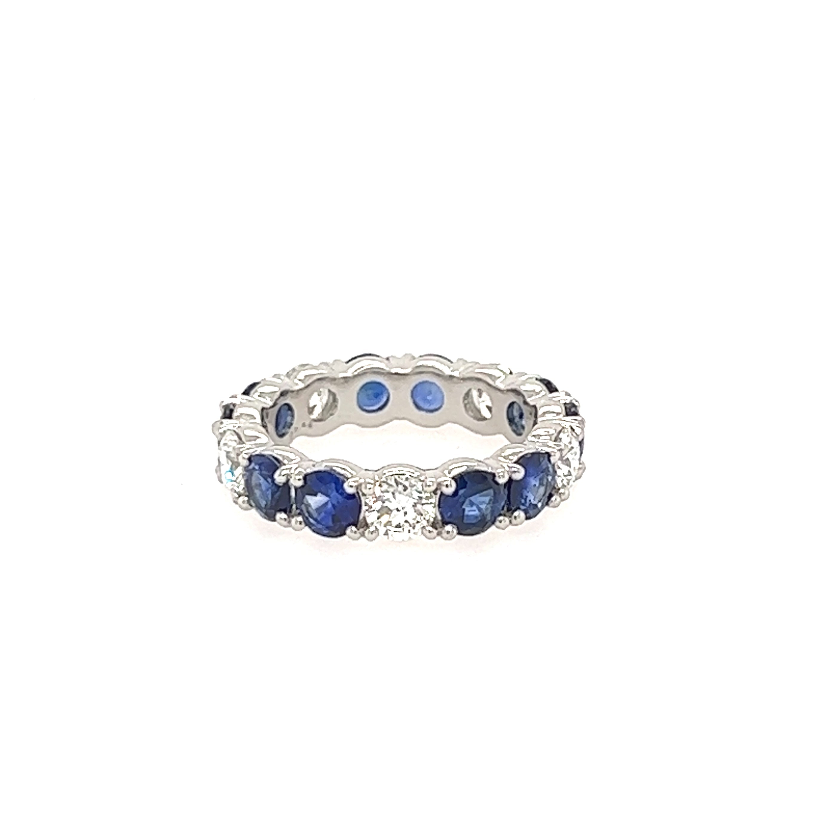 A platinum band ring with prong set blue sapphires and diamonds.