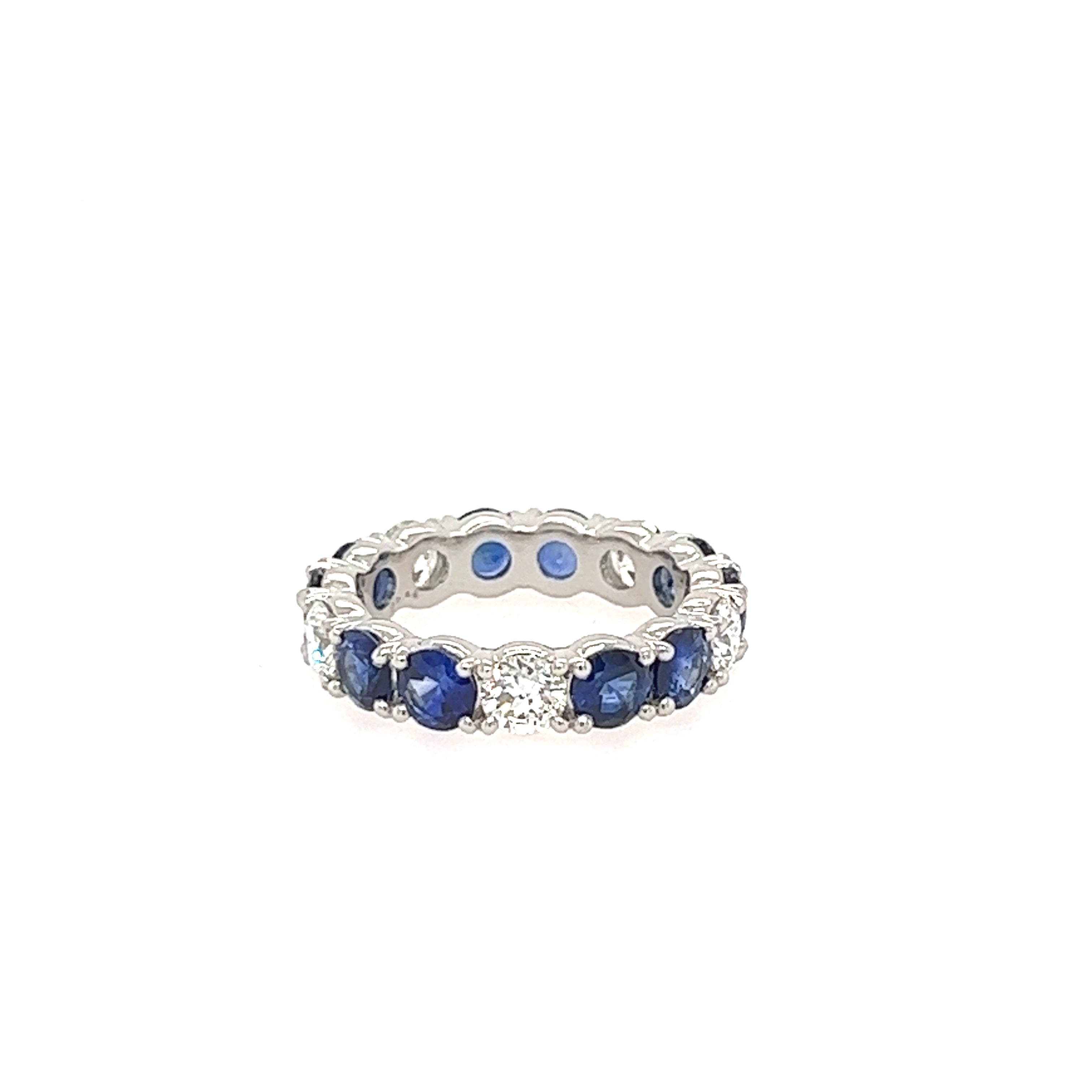 A platinum band ring with prong set blue sapphires and diamonds.