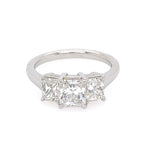 This image features an elegant Platinum and Diamond Three Stone Ring, presented against a simple white background that highlights its intricate details. The ring showcases a classic design with three prominently set radiant-cut diamonds, each encased in a sleek, polished setting.