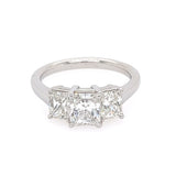 This image features an elegant Platinum and Diamond Three Stone Ring, presented against a simple white background that highlights its intricate details. The ring showcases a classic design with three prominently set radiant-cut diamonds, each encased in a sleek, polished setting.