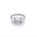 A platinum three stone oval cut diamond ring with a main oval-cut diamond flanked by two smaller, oval-cut diamonds, set in a platinum band.