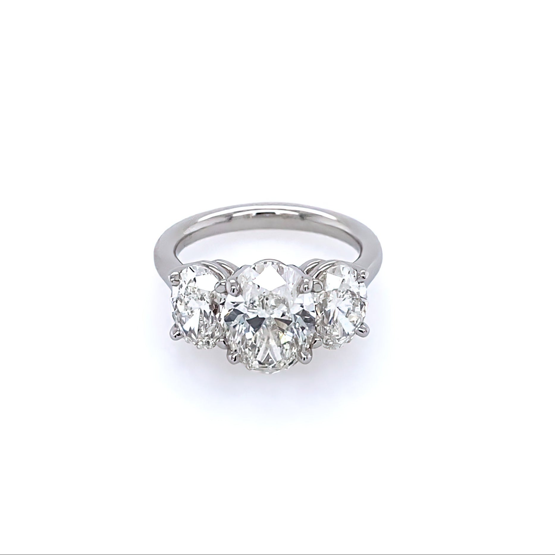 A platinum three stone oval cut diamond ring with a main oval-cut diamond flanked by two smaller, oval-cut diamonds, set in a platinum band.