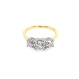 A three-stone diamond ring with a yellow gold band and a platinum prong setting, against a plain white background.
