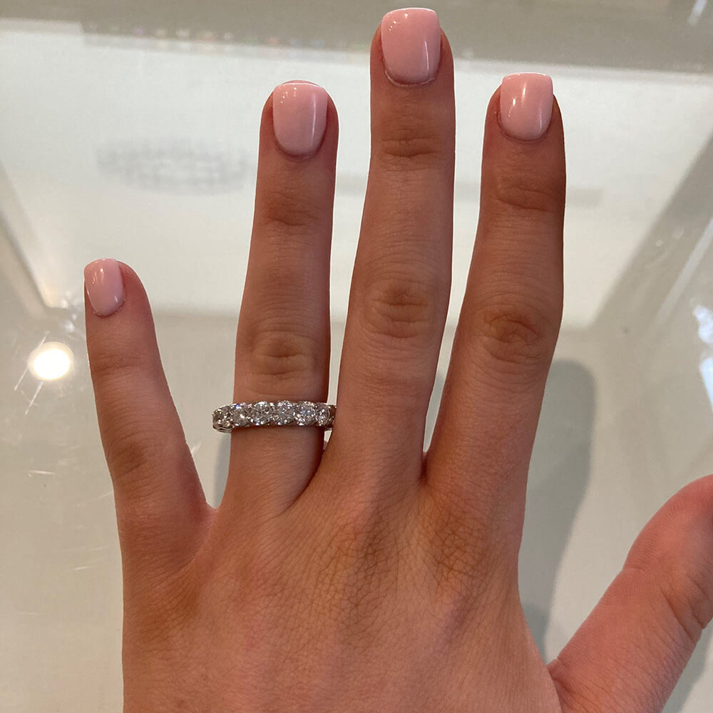woman's Hand wearing a platinum diamond ring with a neutral background