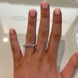 woman's Hand wearing a platinum diamond ring with a neutral background