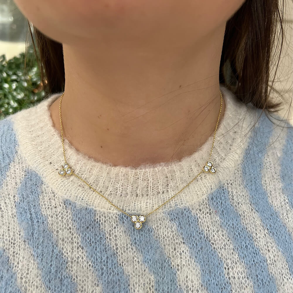 18K yellow gold necklace with floral diamond pendants worn by a person in a blue and white striped sweater.