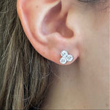 Close-up of an ear wearing a platinum earring with three round stones.