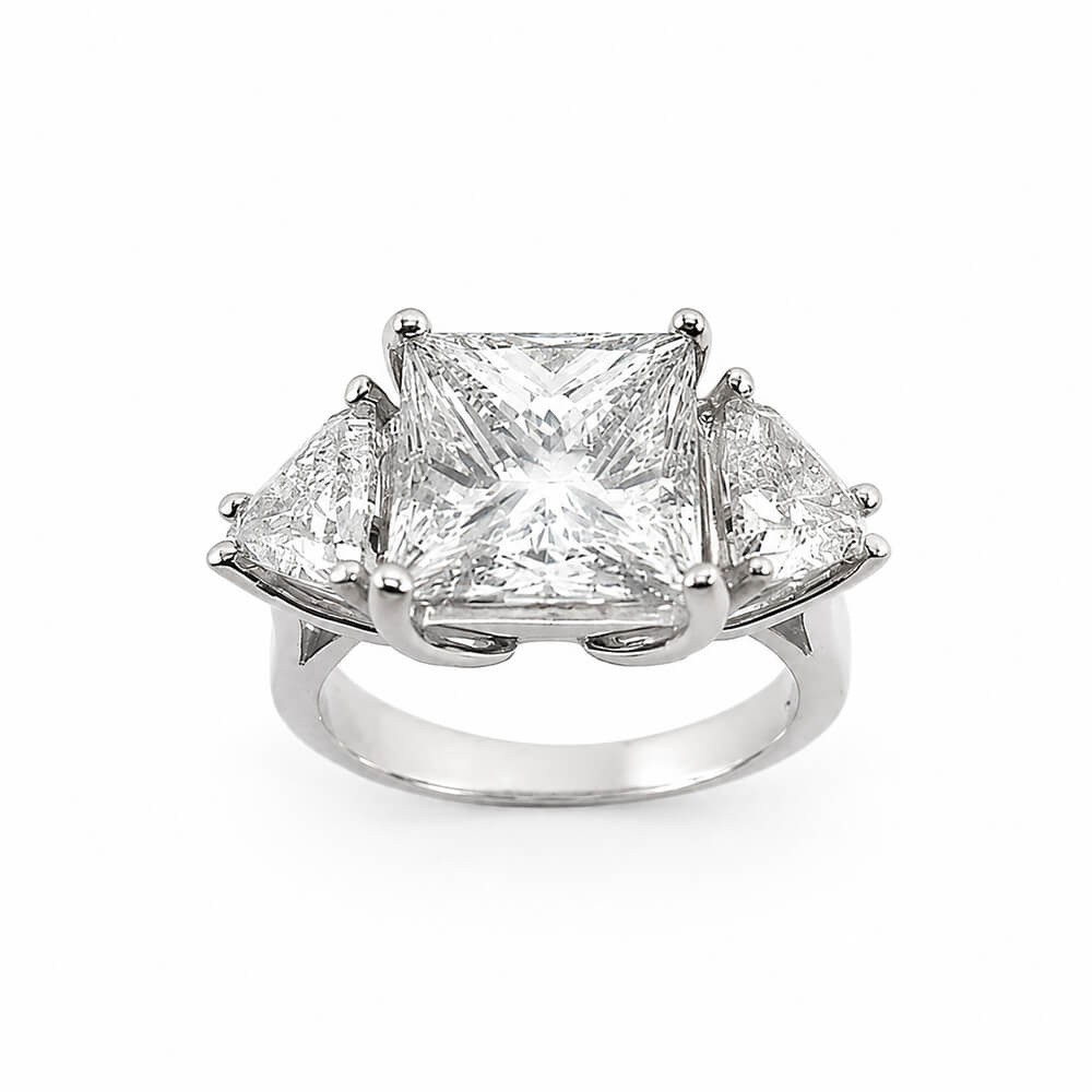 A three-stone diamond ring featuring a central princess-cut diamond flanked by two smaller trillion-cut diamonds in a platinum setting, shown on a plain white background.