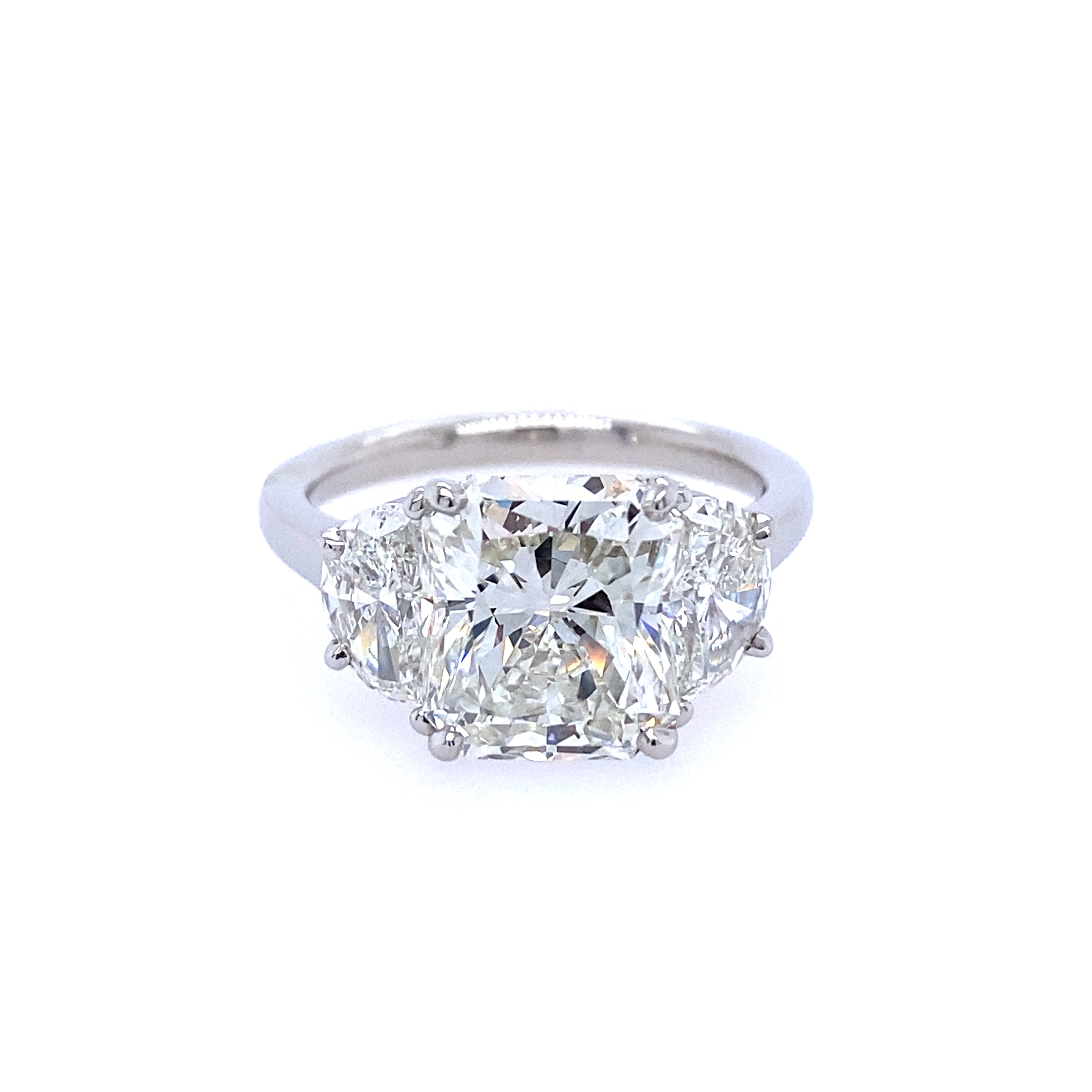 A custom designed radiant cut diamond ring with half moon sides, set in a platinum band
