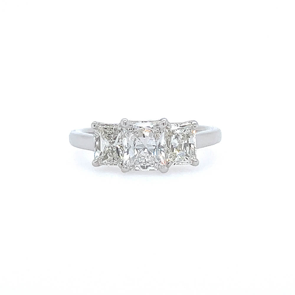 A three-stone diamond ring featuring rectangular radiant-cut diamonds set in a platinum band, centered on a plain white background.