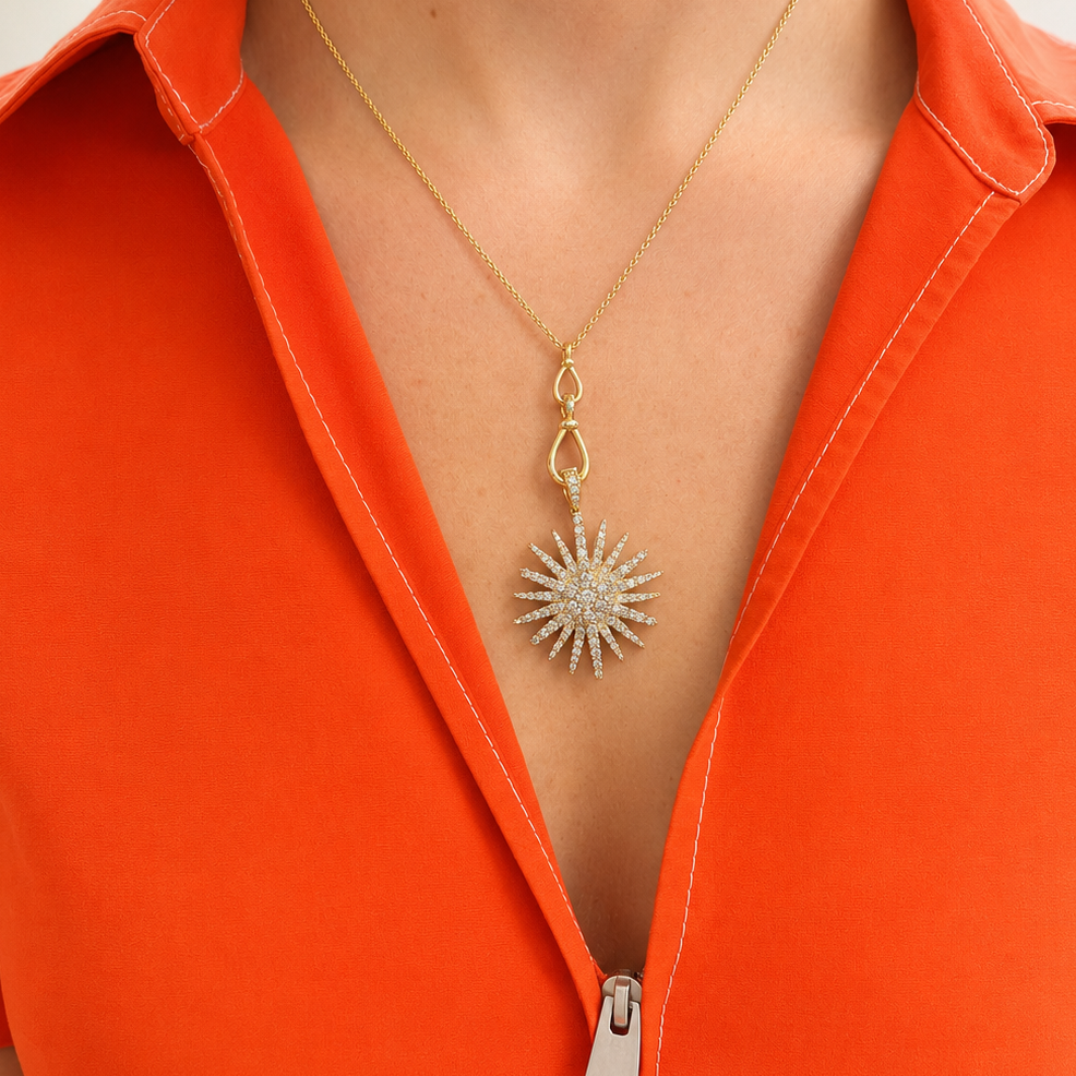 woman wearing a 14K yellow gold dangle link necklace with two teardrop shaped links on a fine gold chain. a diamond starburst pendant hangs from the necklace