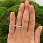 Hand wearing a platinum shared prong set diamond ring 1.62 carats with a blurred green background