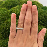 Hand wearing a platinum shared prong set diamond ring 1.62 carats with a blurred green background
