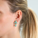Close-up of a woman wearing Elizabeth Locke turquoise drop earrings with a light gray background