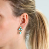 Close-up of a woman wearing Elizabeth Locke turquoise drop earrings with a light gray background