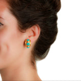 Close-up of a woman wearing gold earrings with turquoise stones on a white background