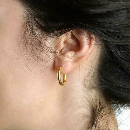 Close-up of an ear wearing a 19K gold hoop earring designed by Elizabeth Locke