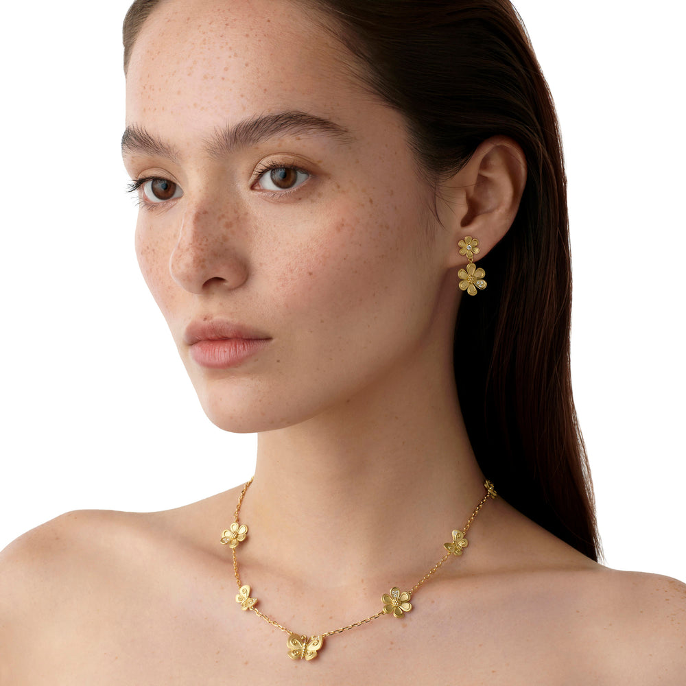 Woman wearing Temple St Clair Golden Flower necklace and earrings 