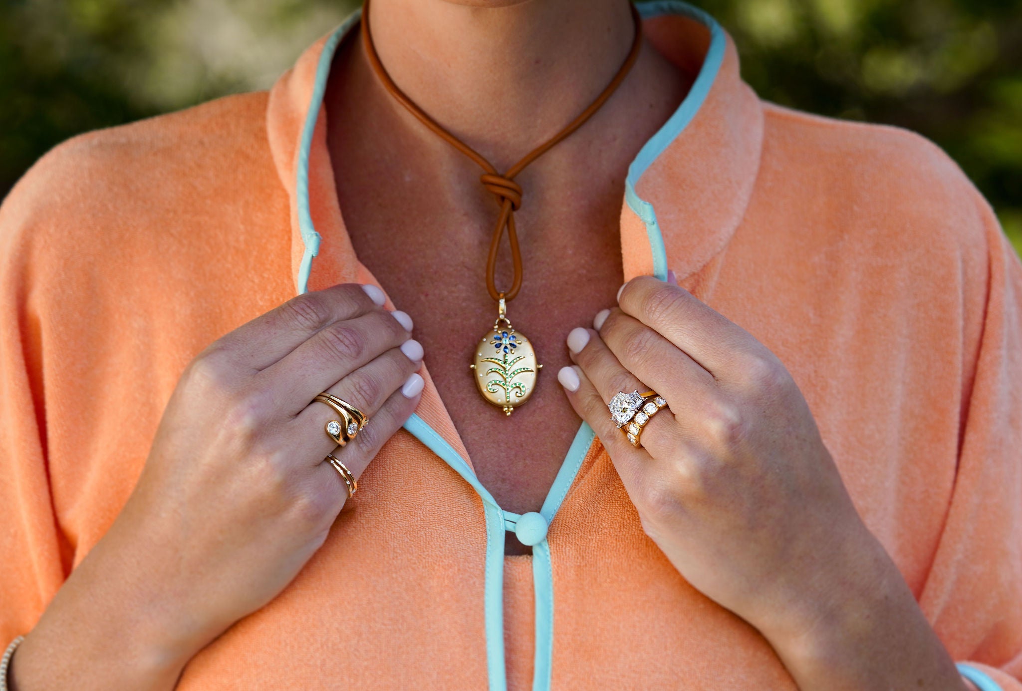Woman wearing a Temple St. Clair necklace with a pendant and multiple diamond rings.