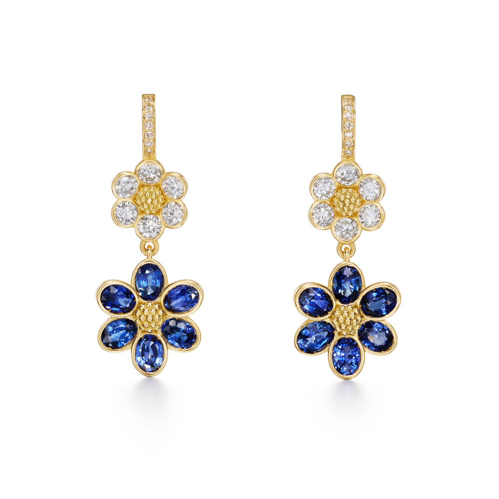 A pair of 18K yellow gold drop earrings featuring diamond accents and blue sapphire flowers designed by Temple St Clair