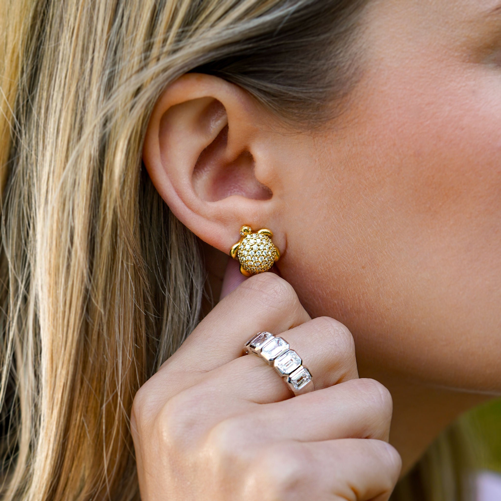 Close-up of a woman wearing gold Turtle earrings with diamonds desiigned by Temple St Clair