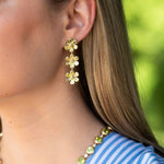 Close-up of a woman wearing 18K gold floral drop earrings 