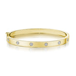 An 18K yellow gold diamond station bangle bracelet with multiple embedded diamonds around its circumference.