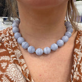 Necklace with blue Agate beads worn by a woman with a patterned garment.