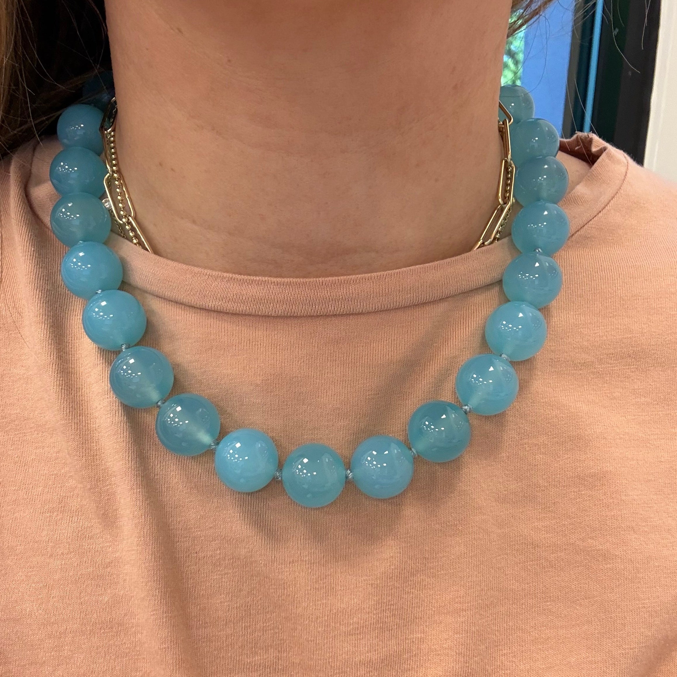 Blue beaded bracelet on a person's wrist against a beige background