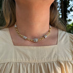 A close-up of an Estate 18K Yellow gold chain necklace with textured, diamond  beads, worn by a model in a beige top.