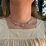 A close-up of an Estate 18K Yellow gold chain necklace with textured, diamond  beads, worn by a model in a beige top.