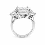 A three-stone diamond ring featuring a large rectangular center diamond and two smaller trillion-cut side diamonds in a polished platinum setting, shown against a plain white background.