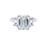 A custom designed platinum diamond ring with a central emerald cut diamond and smaller diamonds set around it.