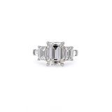 A platinum five-stone ring featuring a central emerald-cut diamond flanked by two emerald-cut diamonds, and tapered baguettes set in a polished silver band against a plain white background.